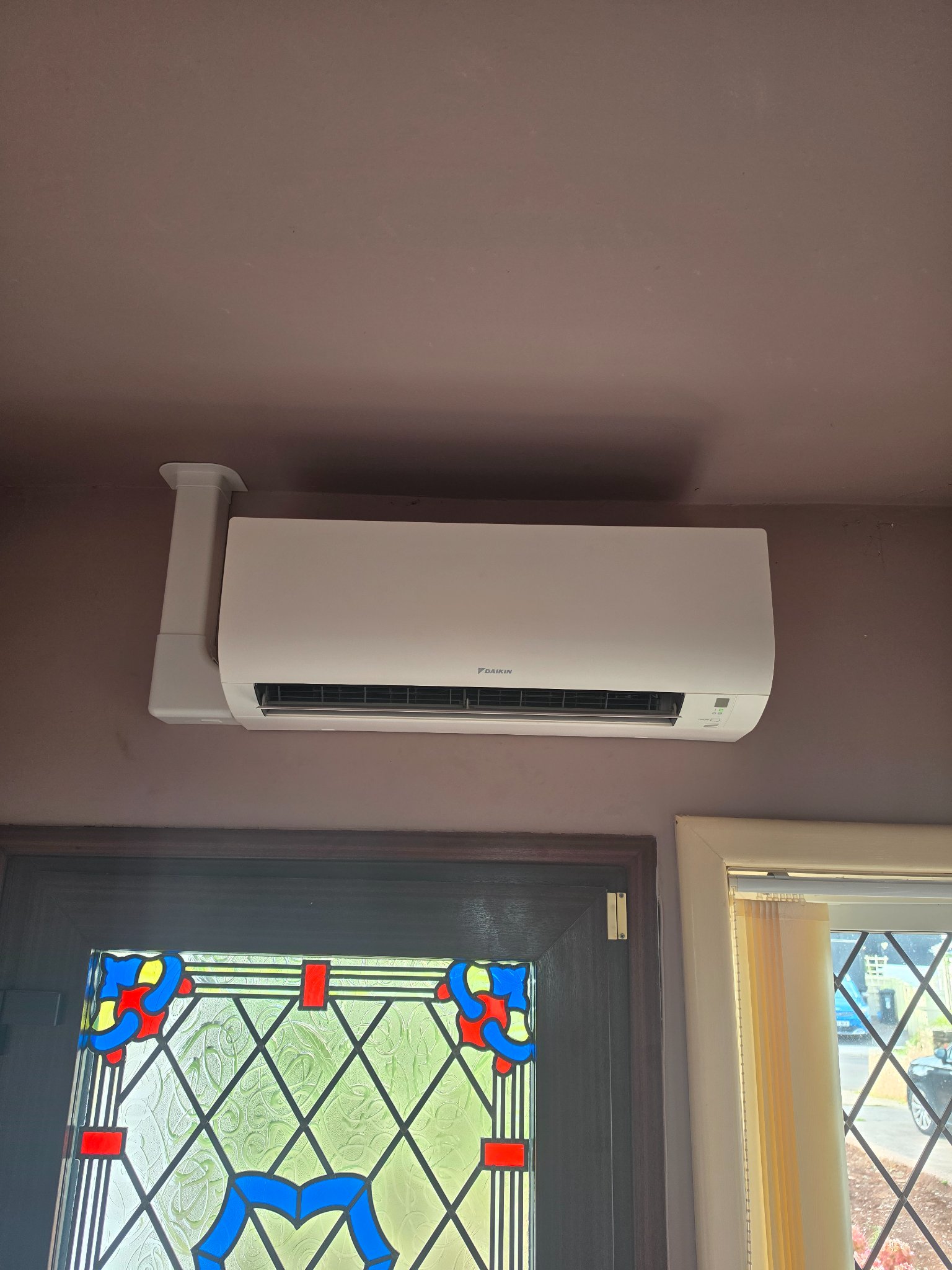 Daikin wall mounted air conditioning indoor unit fitted above the front door in a hallway in North Petherton