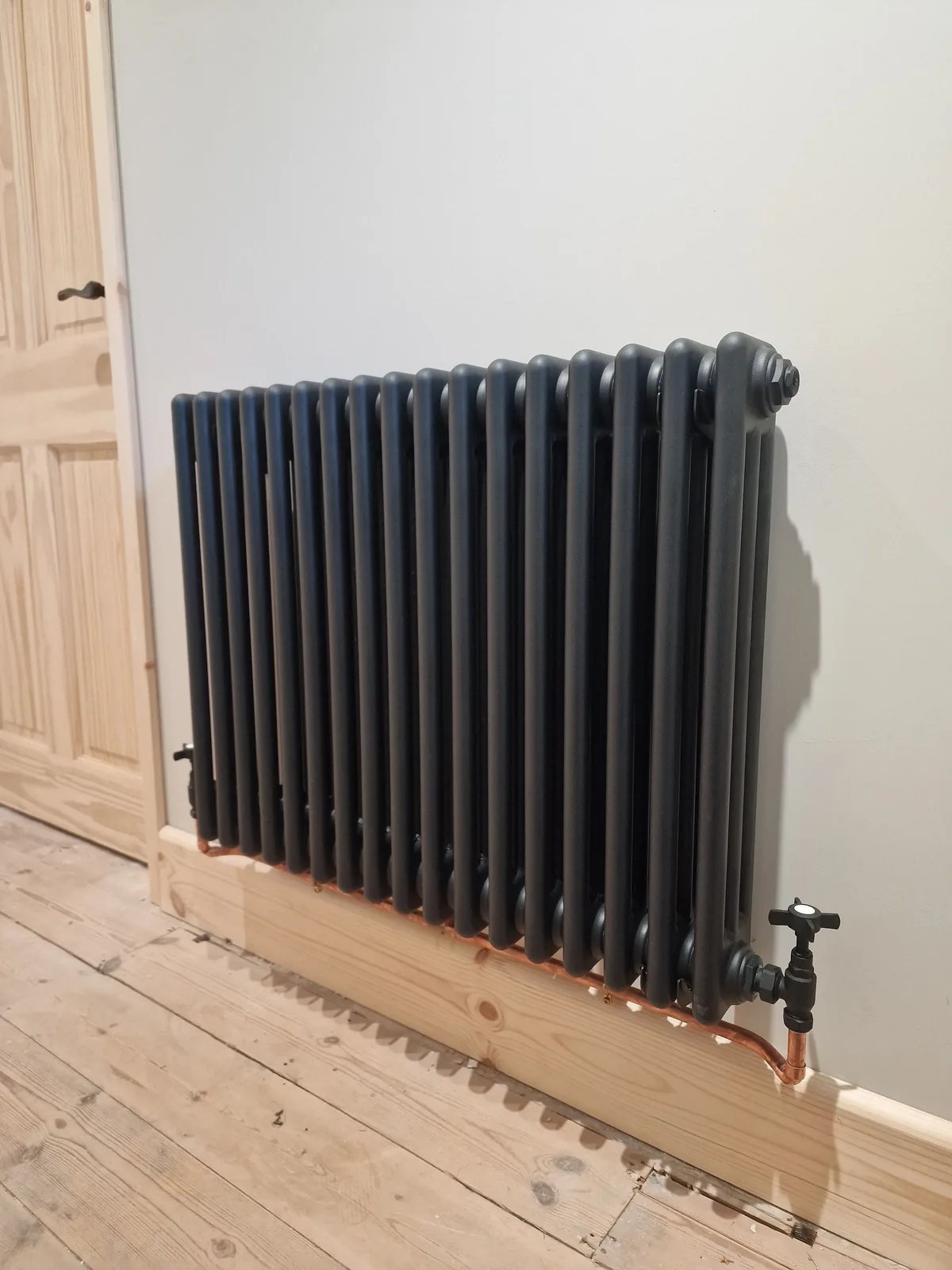 Anthracite column radiator on exposed pipework, installed as part of a heating upgrade