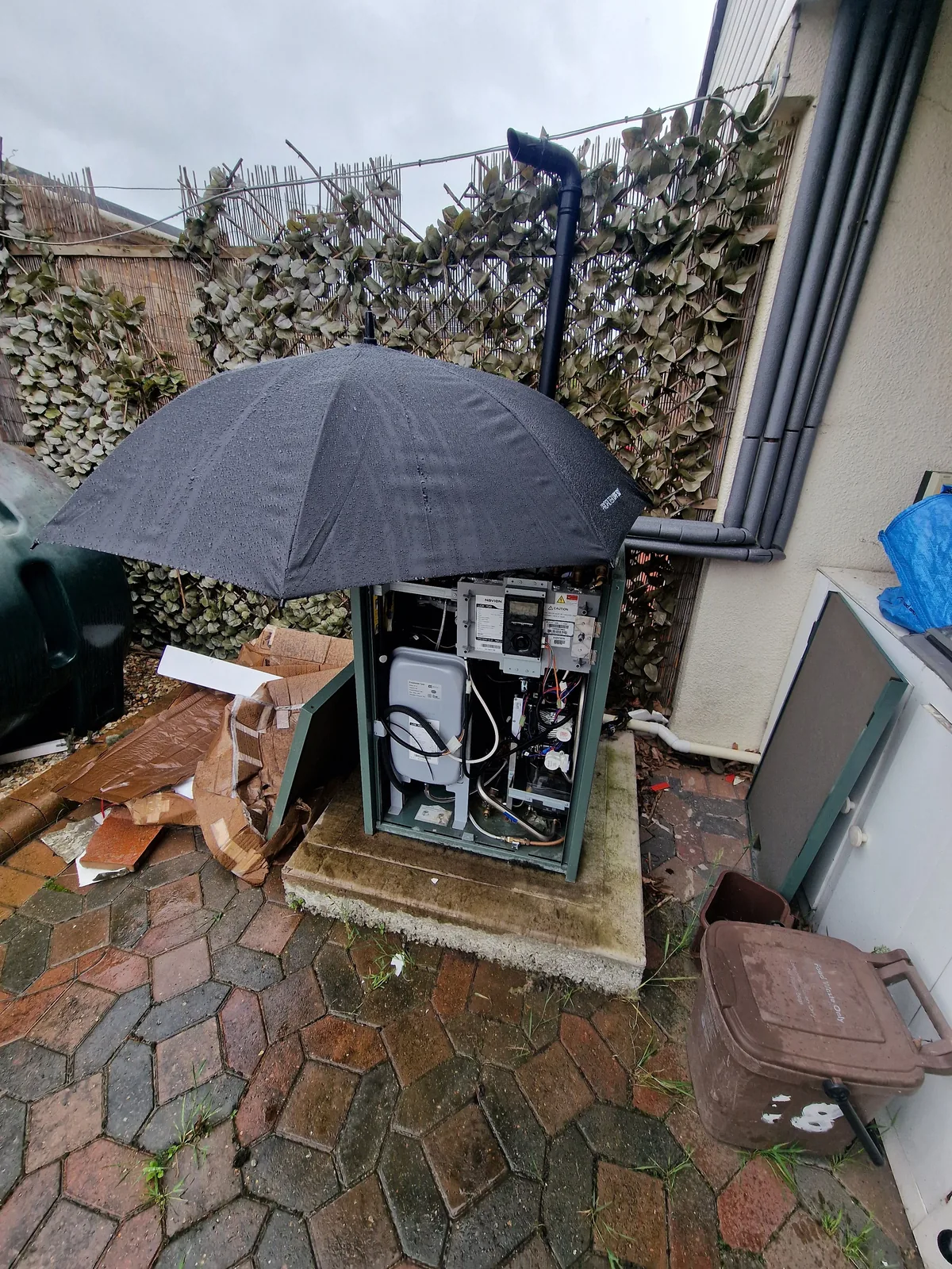 Outdoor oil boiler being diagnosed under an umbrella in wet weather by Fireflow